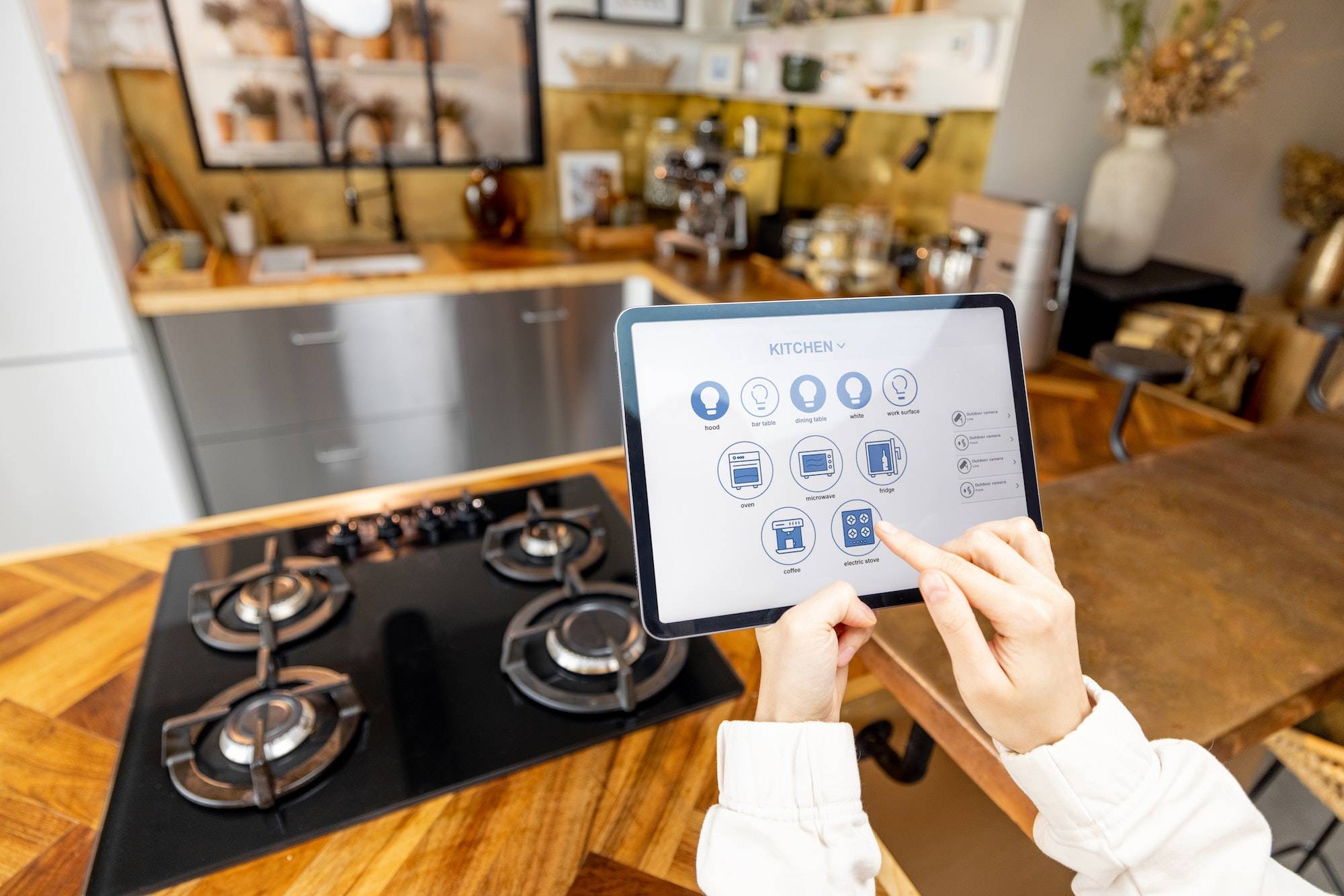 Woman holding digital tablet with running smart home application in the kitchen